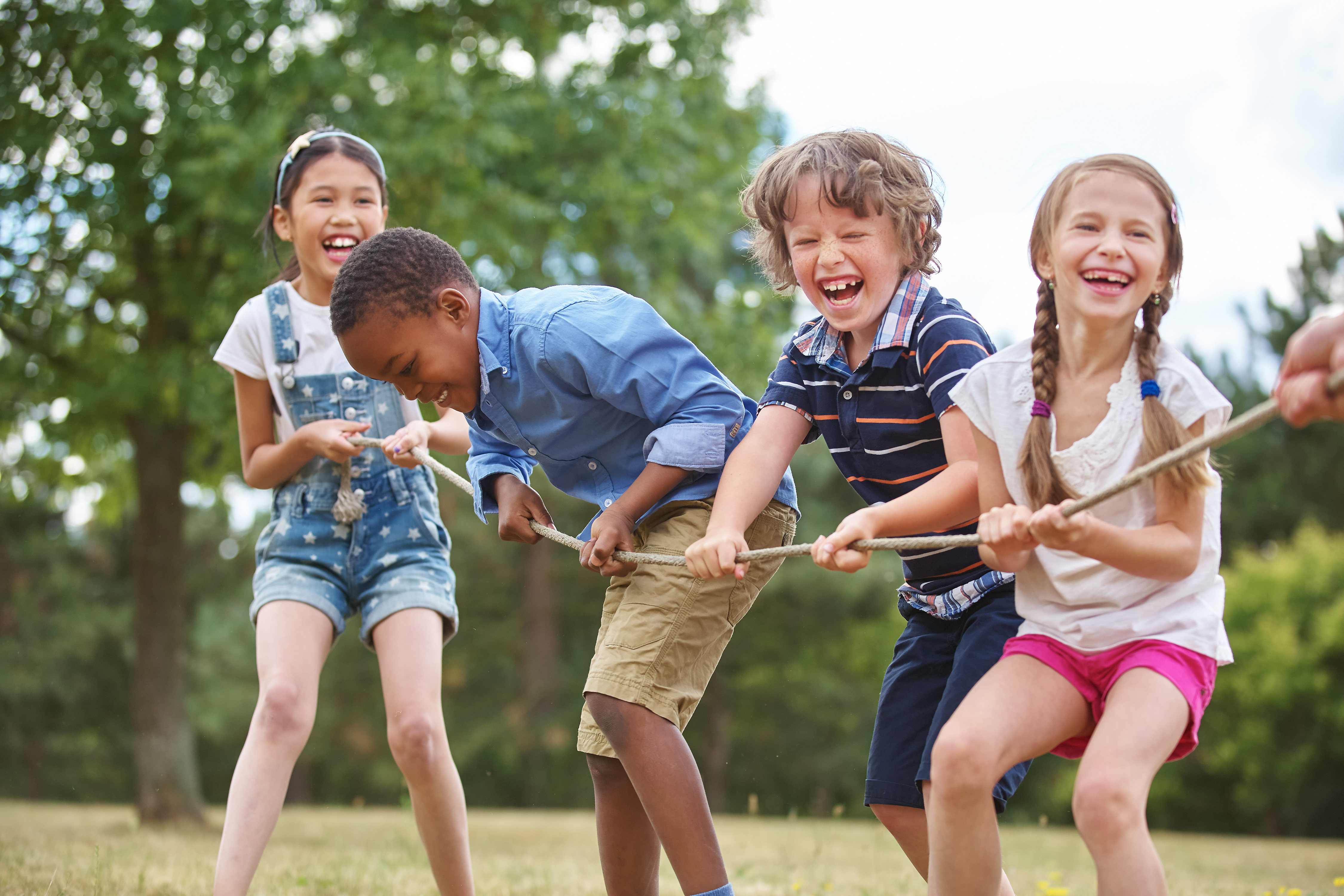 Children laughing and playing tug of war at the park
