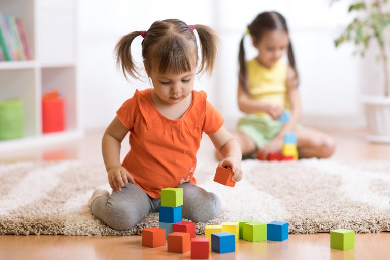 Toddler girls playing with colorful building blocks for child development